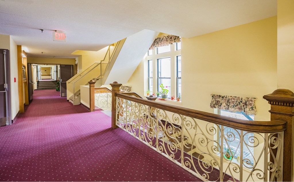 the upstairs hallway of a house with a staircase and a window