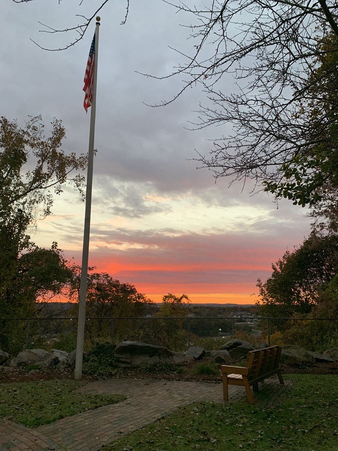 a bench in front of an flag at sunset