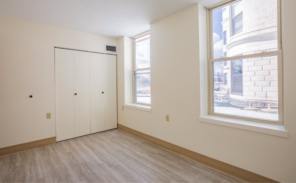 an empty room with two windows and a door