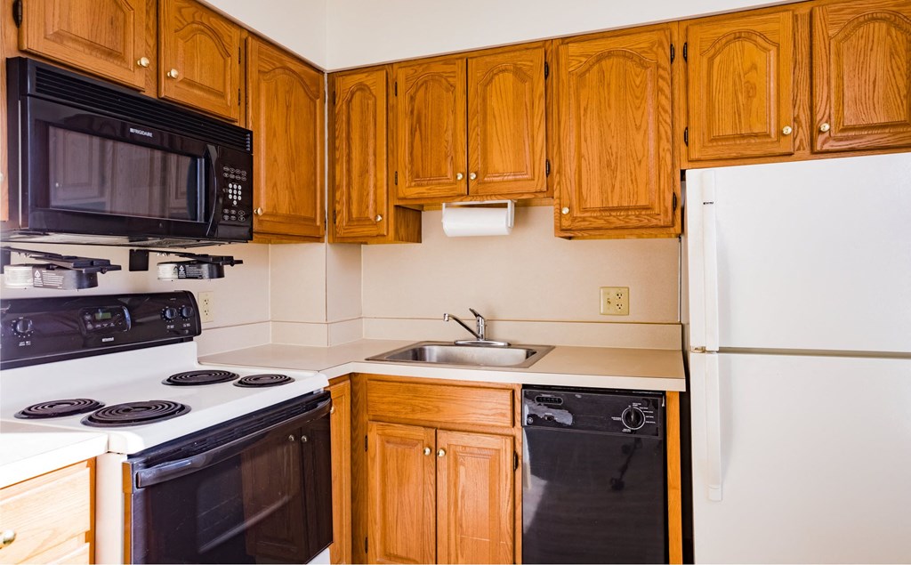 a kitchen with wood cabinets and black appliances and a refrigerator