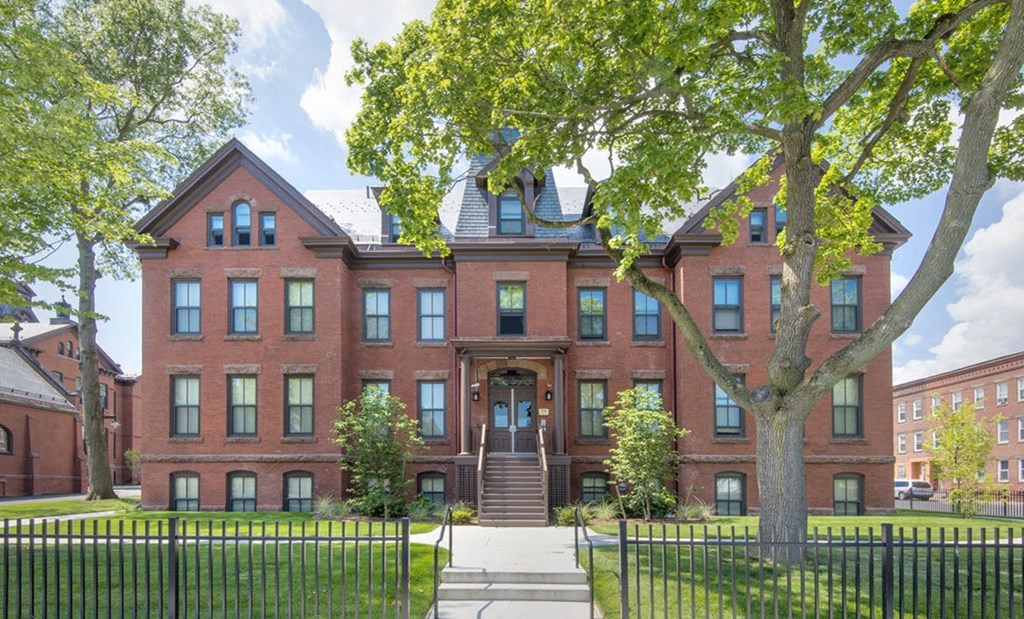 a red brick house with a tree in front of it