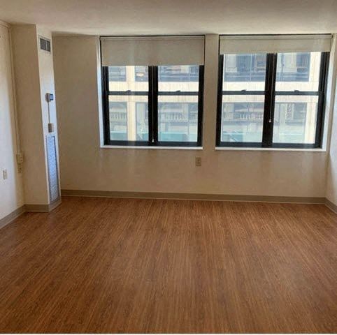 an empty living room with a wooden floor and three windows