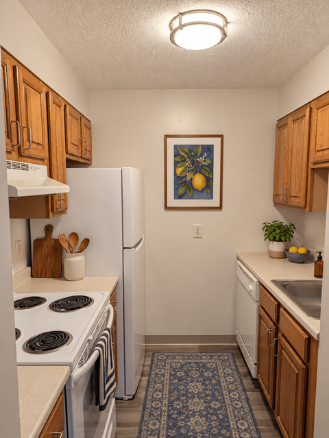 A kitchen with a white fridge and a picture of a lemon hanging on the wall.