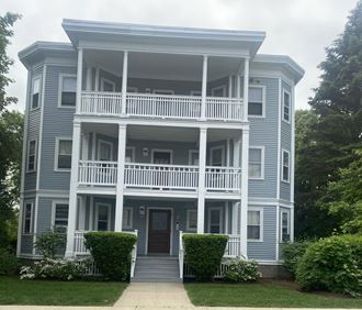 the front of a blue house with a white porch