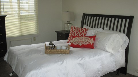 a bed with a white comforter and pillows and a basket of tea