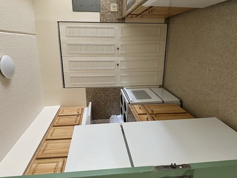 A white cabinet with drawers is mounted on a wall above a wooden table.