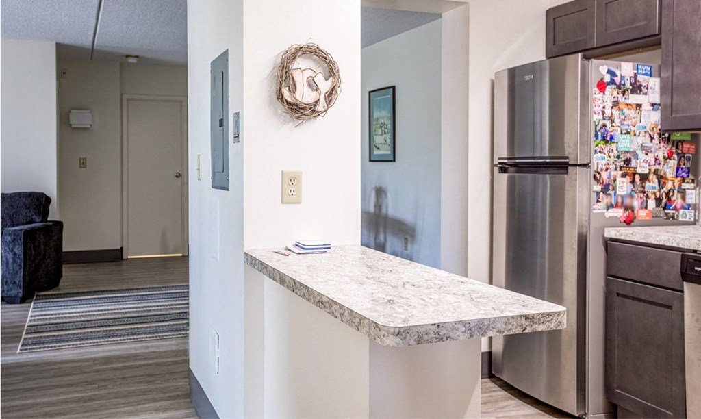 a kitchen with a marble counter top and a stainless steel refrigerator