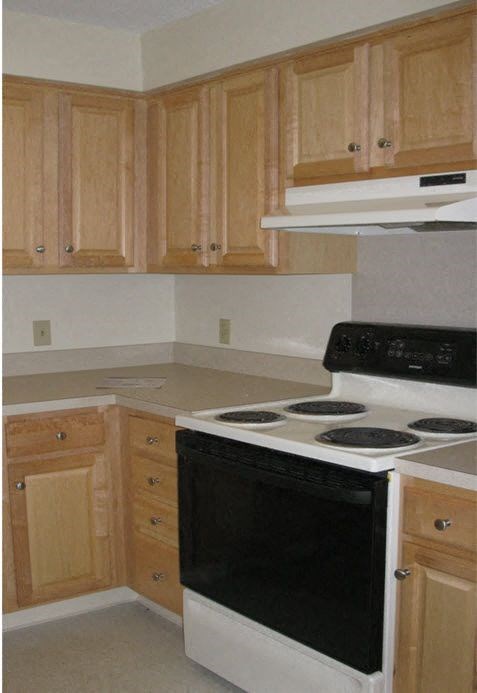 a kitchen with a stove and oven and wooden cabinets
