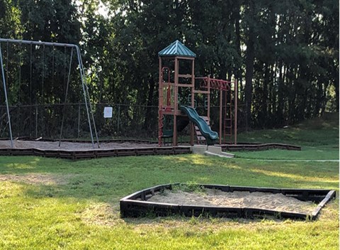 a playground with a slide and a sandbox in a park