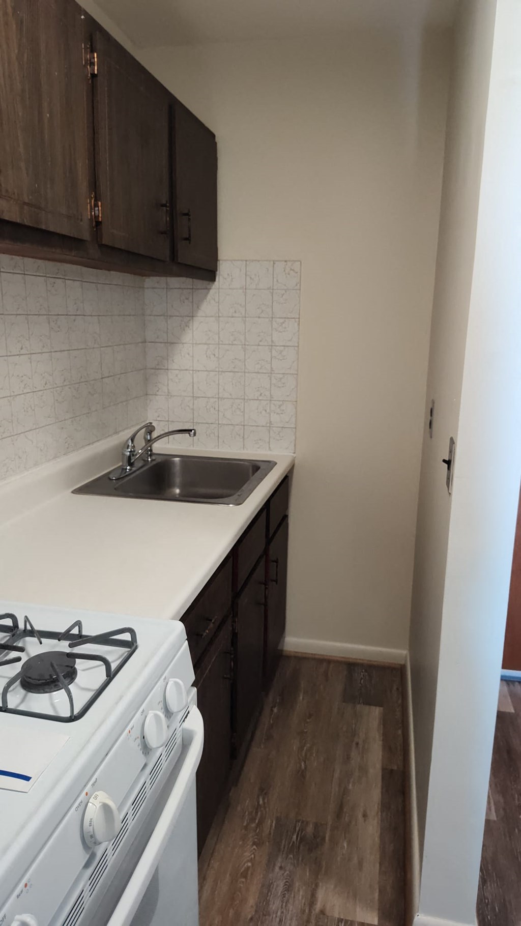 A kitchen with a white stove and wooden cabinets.