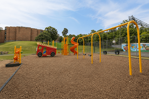 A playground with a red and yellow slide and a yellow monkey bars.
