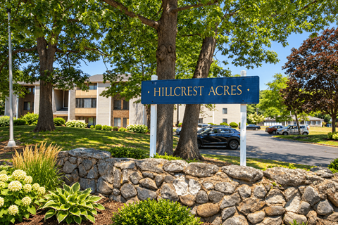 A sign that says Hillcrest Acres stands in front of a building.