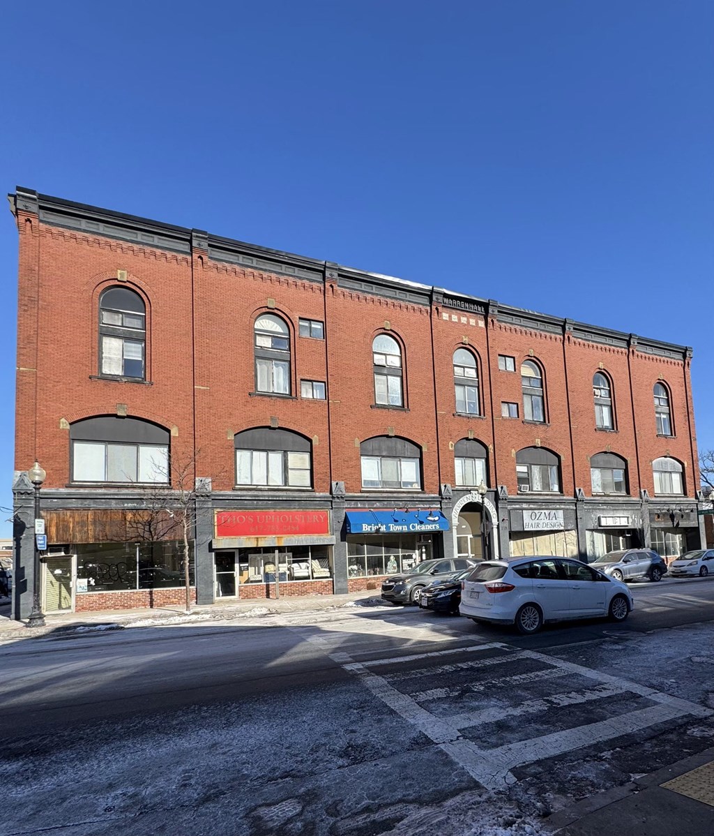 A red brick building with a white car parked in front of it.