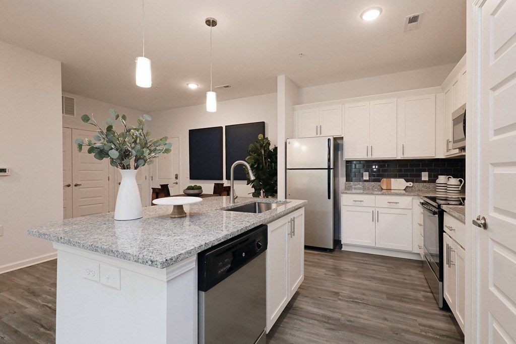 a kitchen with white cabinets and a marble counter top and a stainless steel refrigerator
