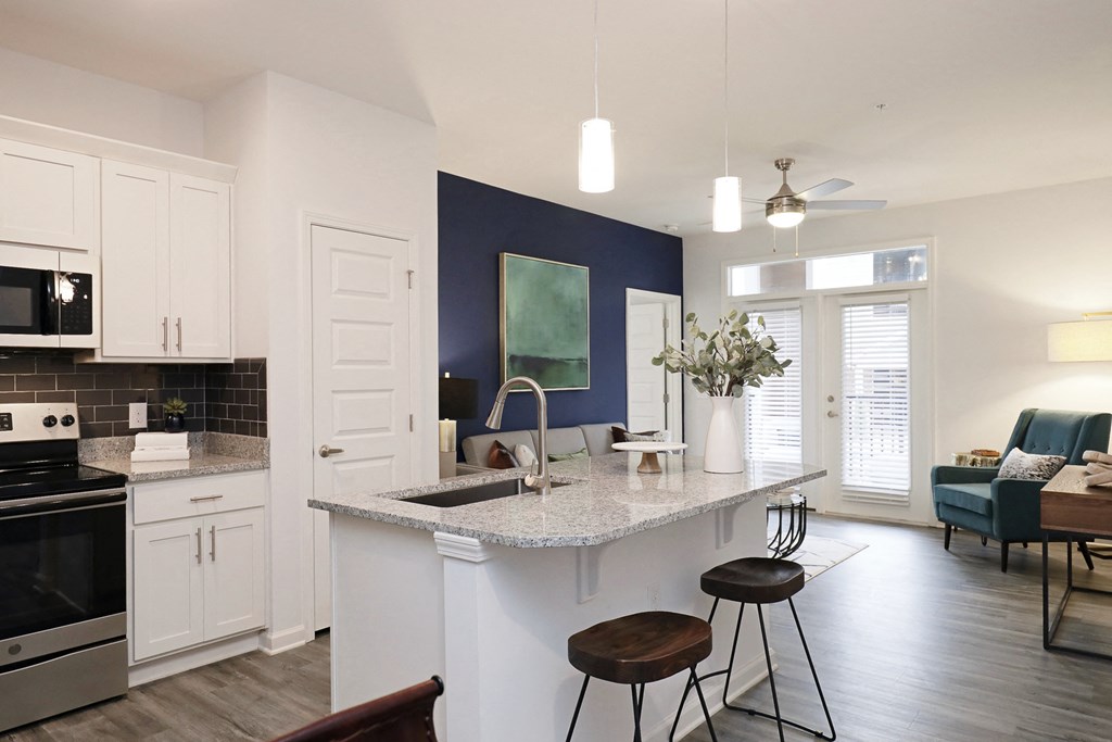 a kitchen and living room with white cabinets and a counter top