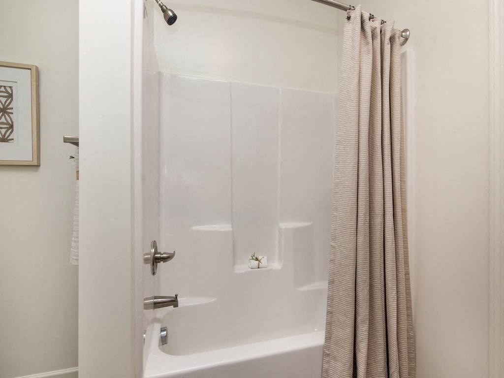 a white bath tub sitting next to a shower curtain at Ardmore at the Trail, North Carolina