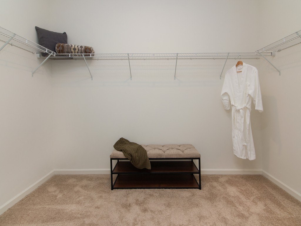a white room with a white robe hanging on the wall and a white bench in the middle at Ardmore at the Trail, Indian Trail, NC
