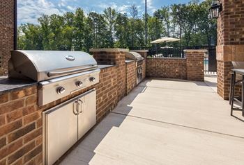 an outdoor kitchen with a grill and a patio with a table and chairs at Ardmore at Bryton, Huntersville