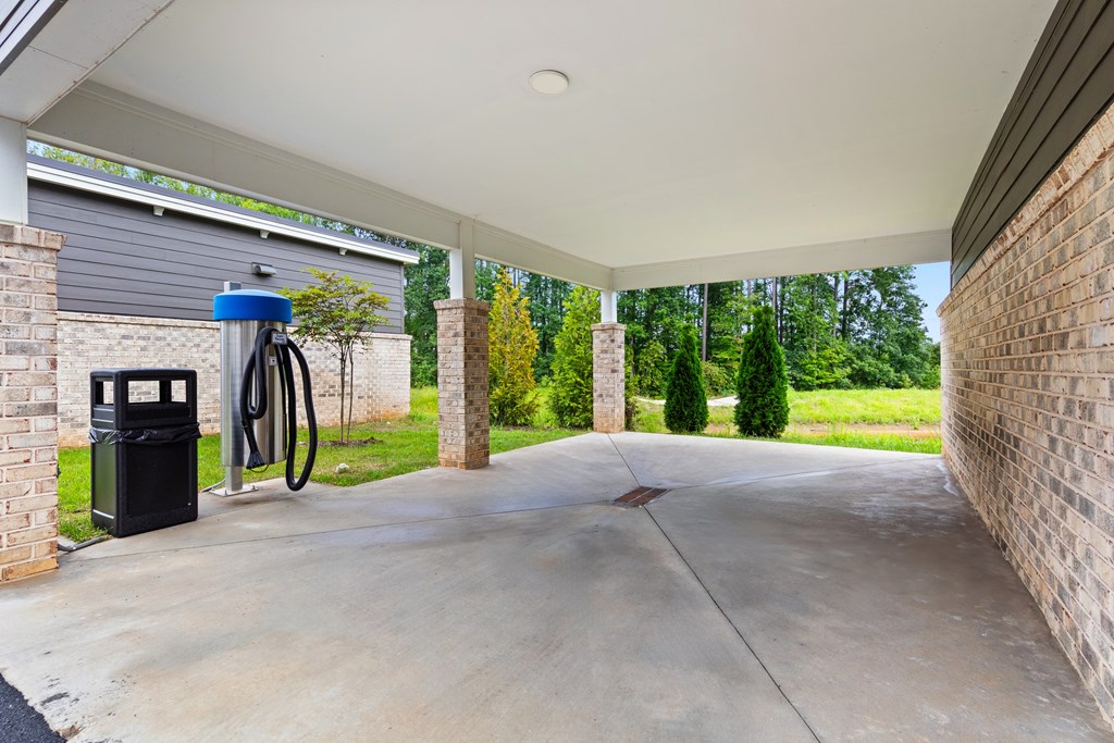 A car is parked in a garage with a blue canister and a hose at Views at Flowers Apartments, North Carolina, 27527