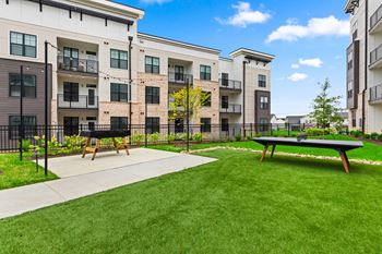 A sunny day at apartment complex with a green lawn and picnic table at Views at Flowers Apartments, Clayton, NC