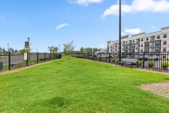 A grassy park with a fence and a building in the background at Views at Flowers Apartments, Clayton, North Carolina