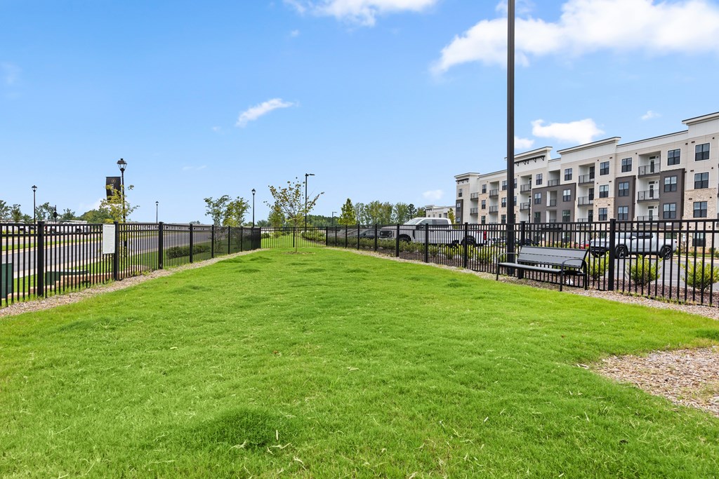 A grassy park with a fence and a building in the background at Views at Flowers Apartments, Clayton 27527