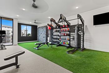 A home gym with a green artificial turf floor and a variety of exercise equipment at Views at Flowers Apartments, Clayton, NC