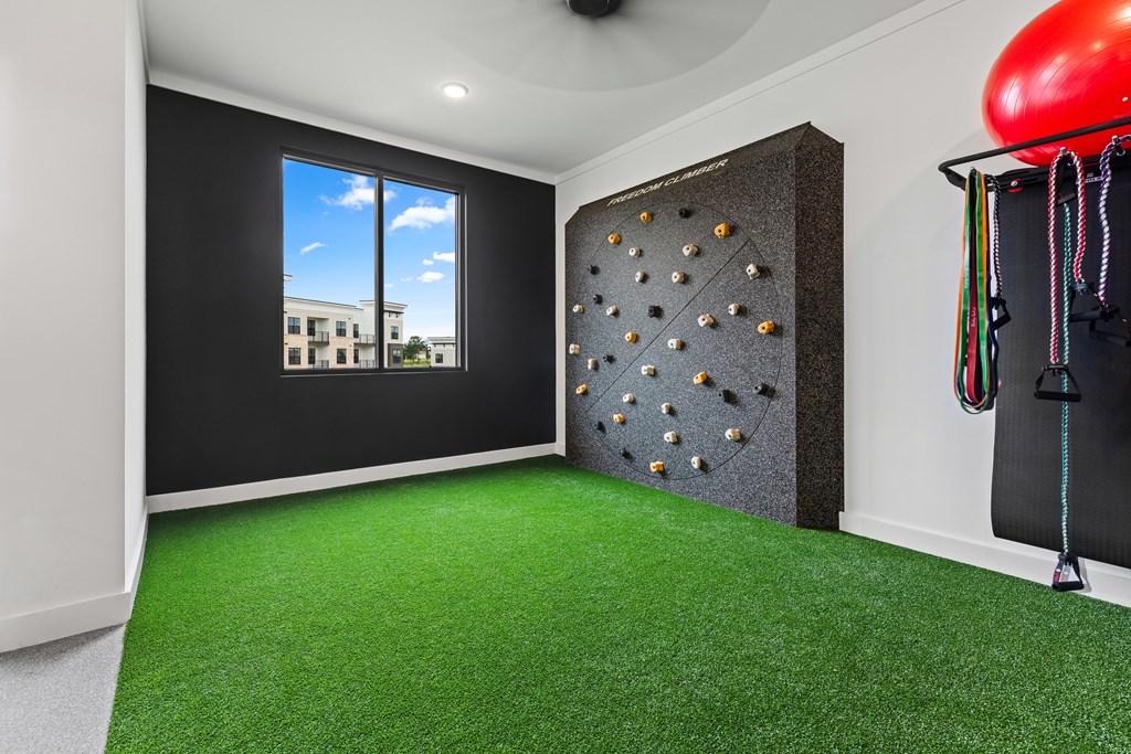 A room with a green carpet and a climbing wall at Views at Flowers Apartments, Clayton, NC