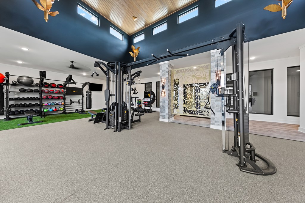 A gym with a variety of equipment including a squat rack, a bench, and a barbell at Views at Flowers Apartments, North Carolina, 27527