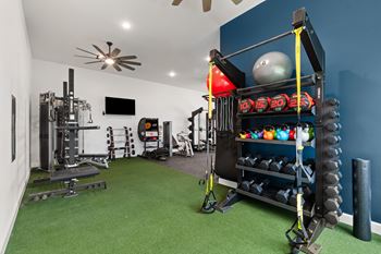 A home gym with a green carpet and various exercise equipment.