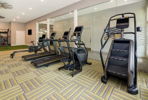 a spacious fitness room with cardio equipment and a large window at Ardmore at Bryton, Huntersville, NC