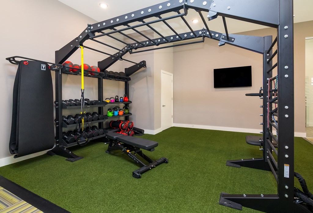 a home gym with green carpet and a black and yellow exercise equipment  at Ardmore at Bryton, Huntersville