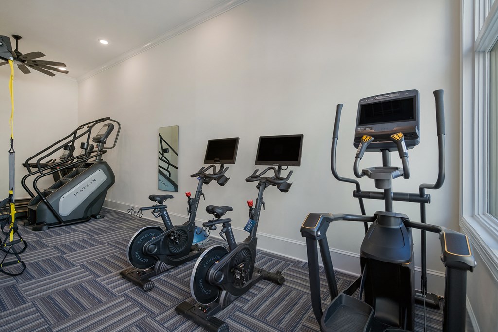 a gym with cardio equipment and weights in a room with a window