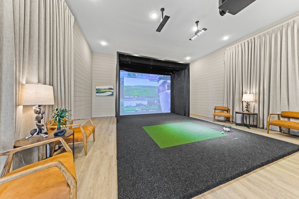 A modern living room with a large screen and comfortable seating at Views at Flowers Apartments, North Carolina