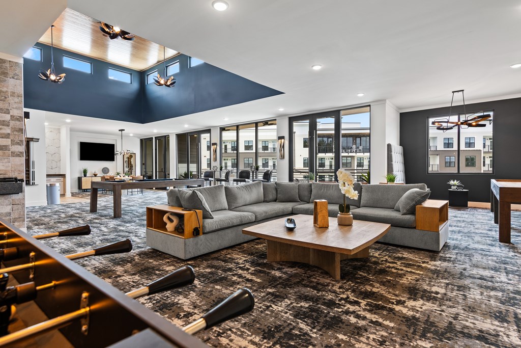 A modern living room with a fireplace and a large grey sofa at Views at Flowers Apartments, North Carolina