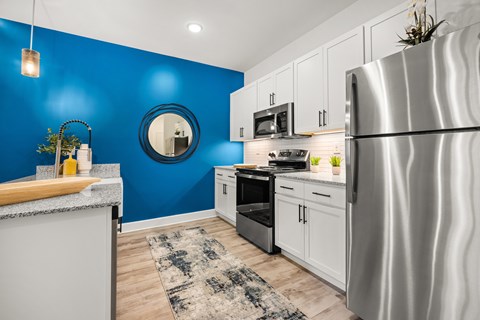 A modern kitchen with a blue wall and stainless steel appliances.