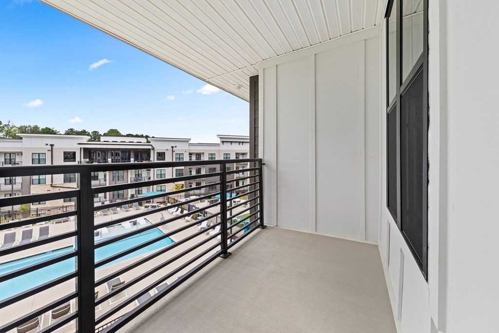 A balcony with a pool and a building in the background.