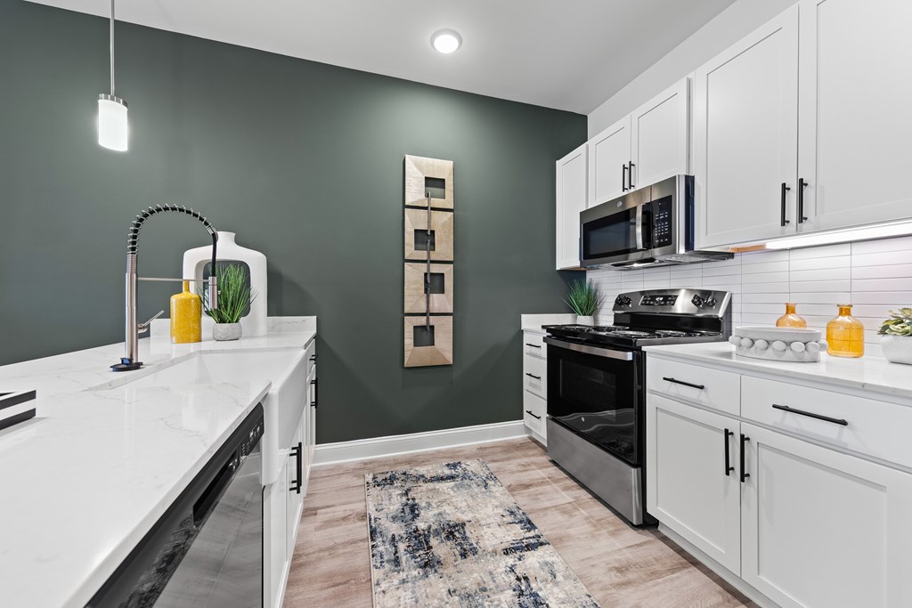 A modern kitchen with white cabinets and a black stove top.