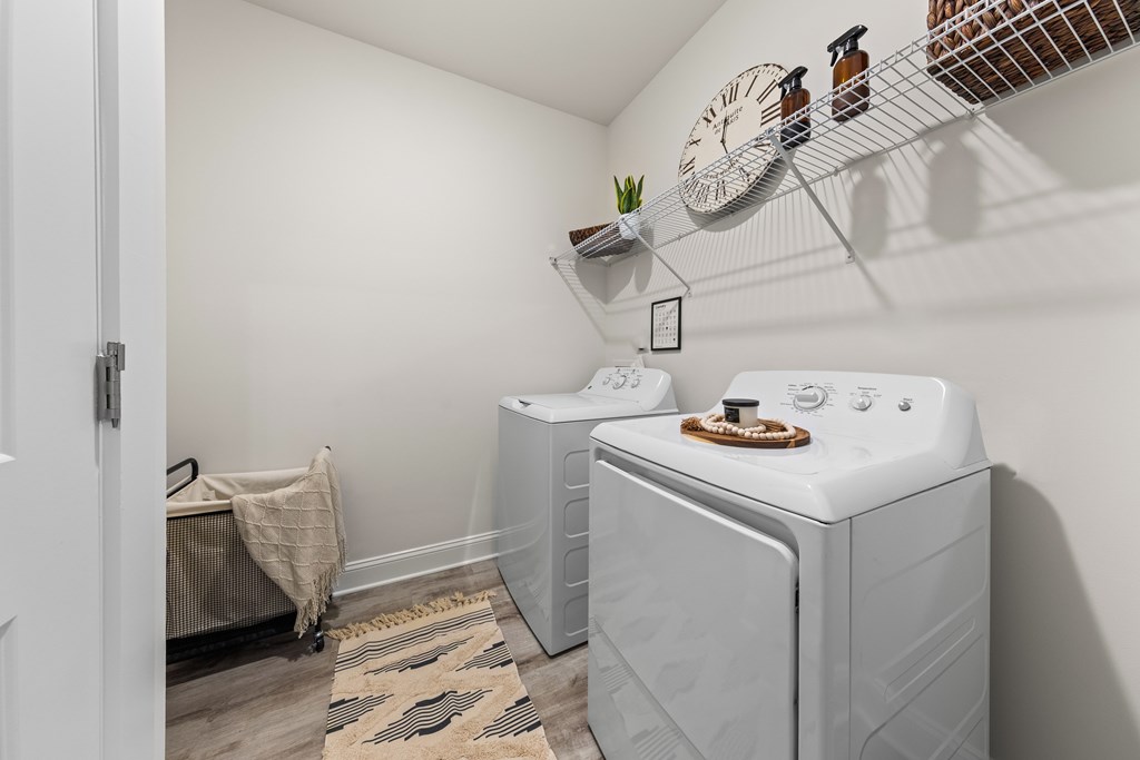 A laundry room with a washer and dryer and a clock on the wall at Views at Flowers Apartments, Clayton