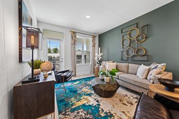 A living room with a brown leather couch and a blue and white rug at Views at Flowers Apartments, Clayton 27527