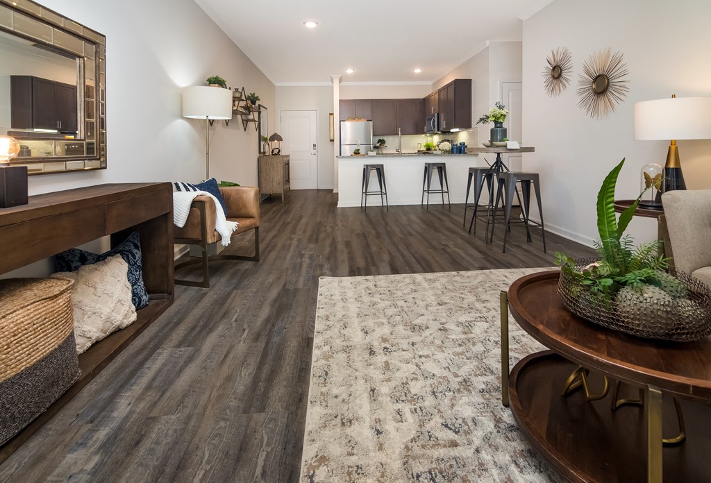 a living room with hardwood flooring and a kitchen in the background