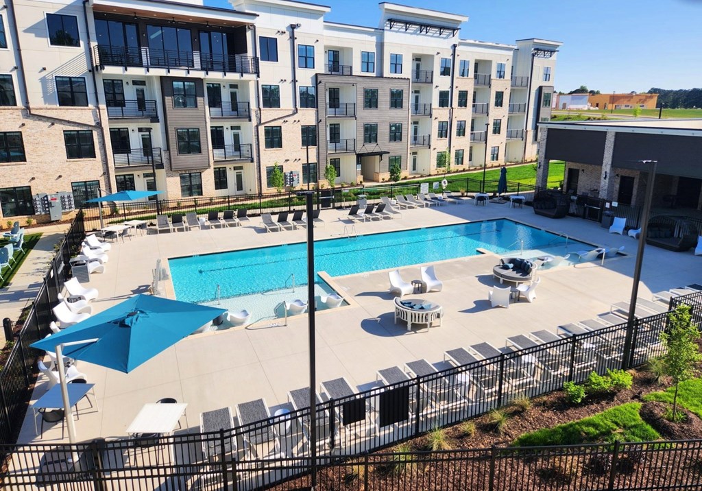 A large swimming pool surrounded by a black fence and lounge chairs at Views at Flowers Apartments, Clayton