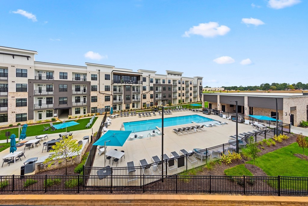 A large outdoor pool surrounded by lounge chairs and umbrellas at Views at Flowers Apartments, Clayton, NC, 27527
