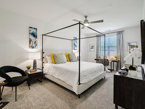 A bedroom with a four poster bed and a chair.