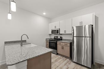 A modern kitchen with a granite countertop and stainless steel appliances.