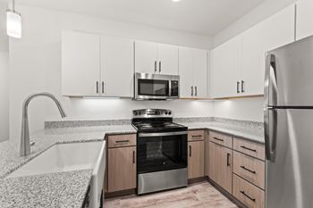A modern kitchen with a stainless steel refrigerator, microwave, and oven.