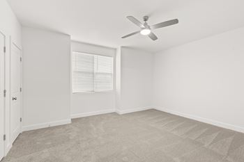 A room with a ceiling fan and carpeted floor.