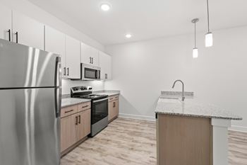 A kitchen with a stainless steel refrigerator, microwave, oven, and sink.
