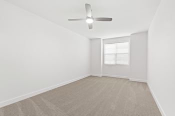 A room with a ceiling fan and carpeted floor.