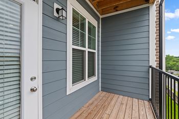 A deck with a white door and a window with white blinds.
